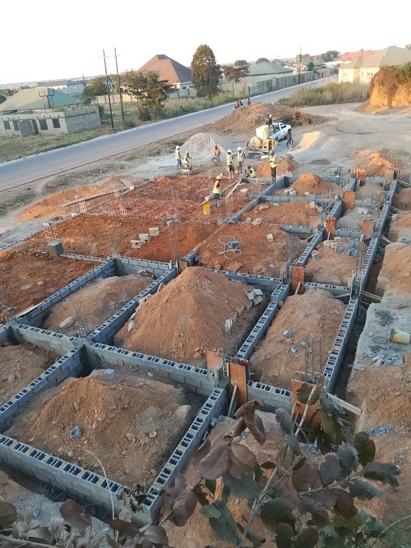 Aerial view of concrete foundation beams and column starter bars with crew working on site