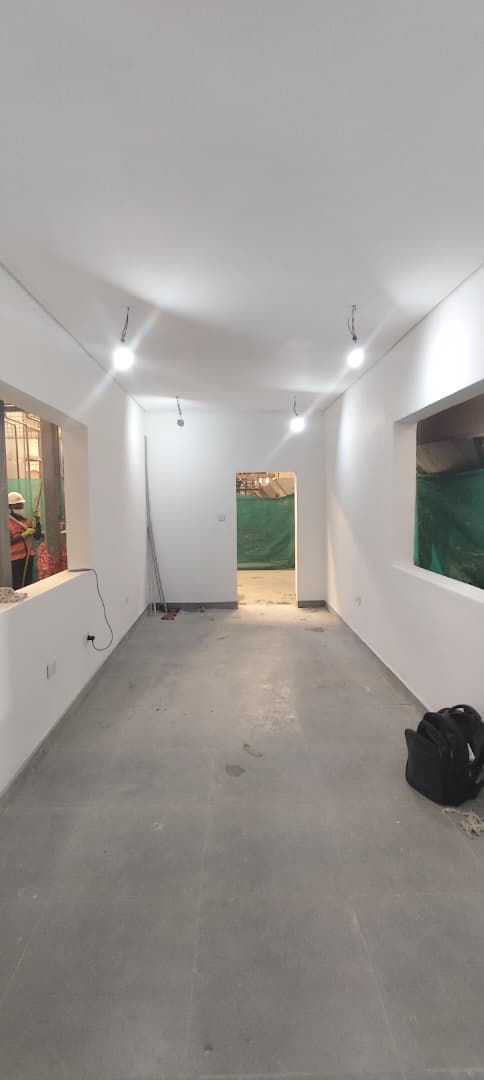 Freshly plastered and painted interior corridor with recessed lighting nearing completion
