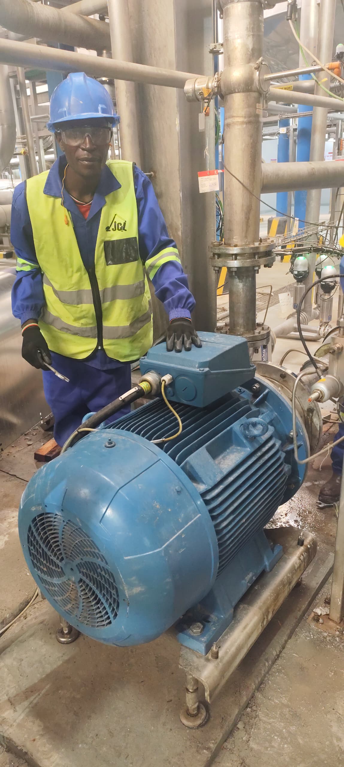 JCL technician in hard hat and branded vest servicing a large industrial motor