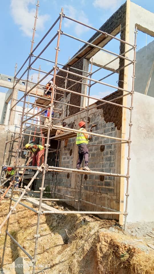 Workers plastering an external blockwork wall from scaffolding platforms