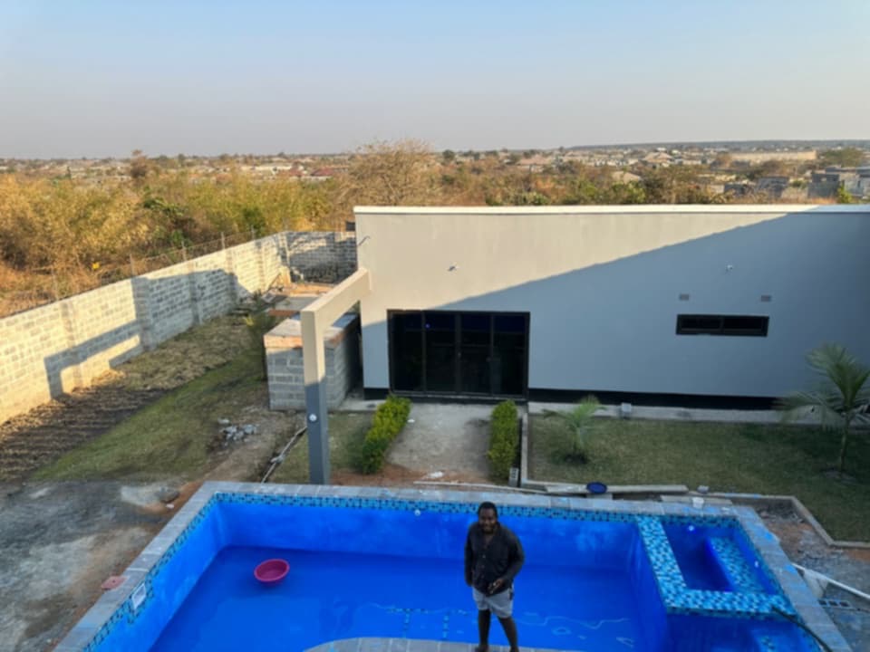 Aerial view of a completed swimming pool shell beside a modern residence