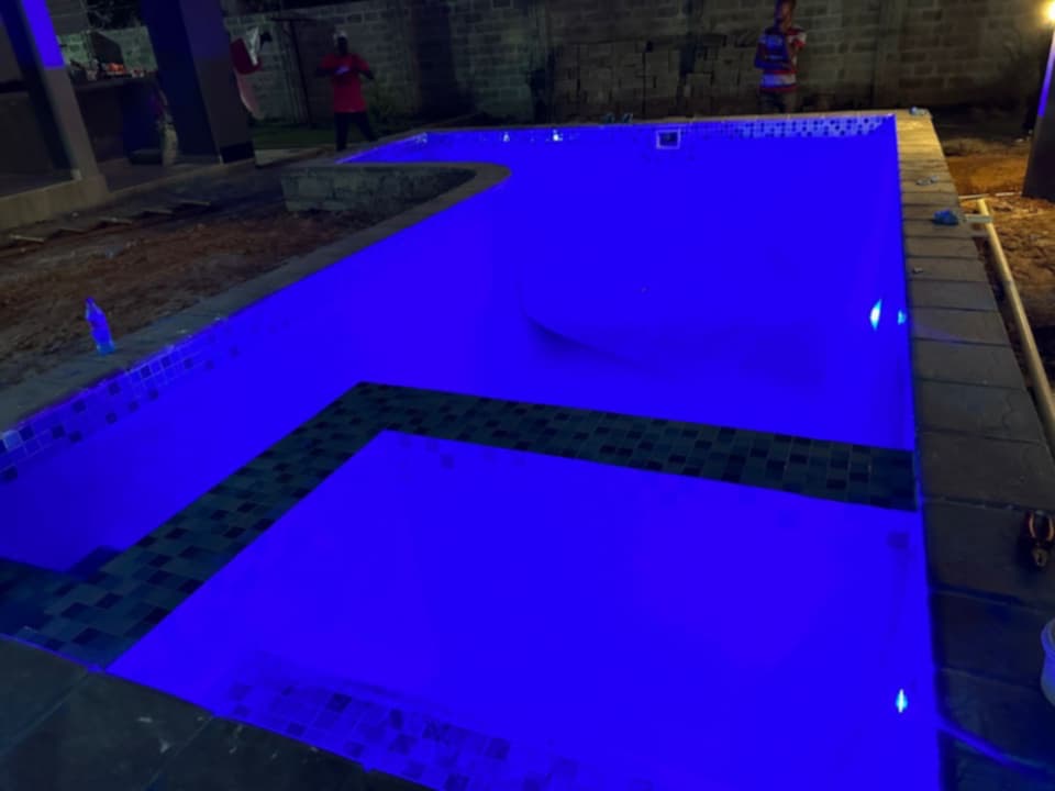 Illuminated residential swimming pool nearing completion in a courtyard setting