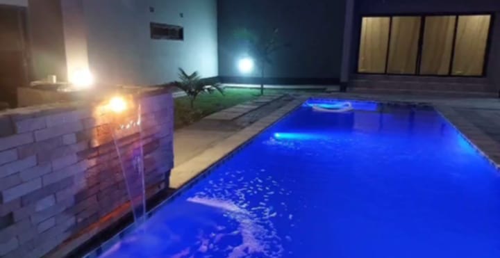 Illuminated swimming pool with stone water feature and cascading waterfall