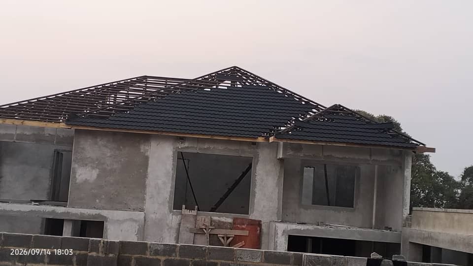 Steel roof trusses and charcoal roof tiles being installed on a double-storey residence under construction