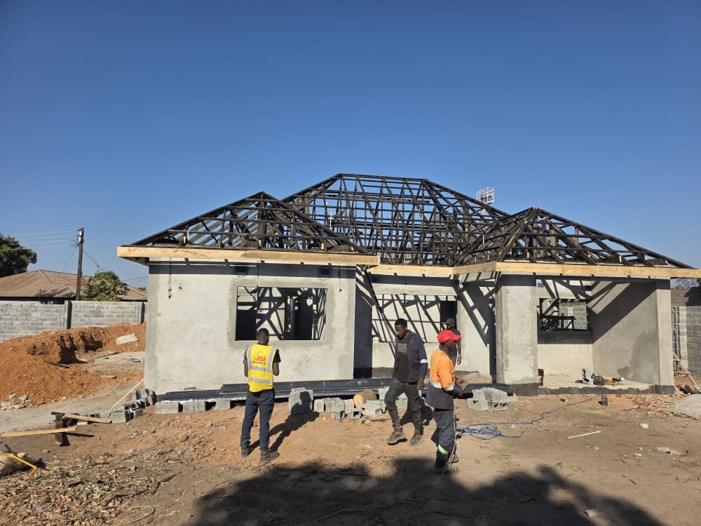 JCL roofing team reviewing steel trusses under a clear blue sky